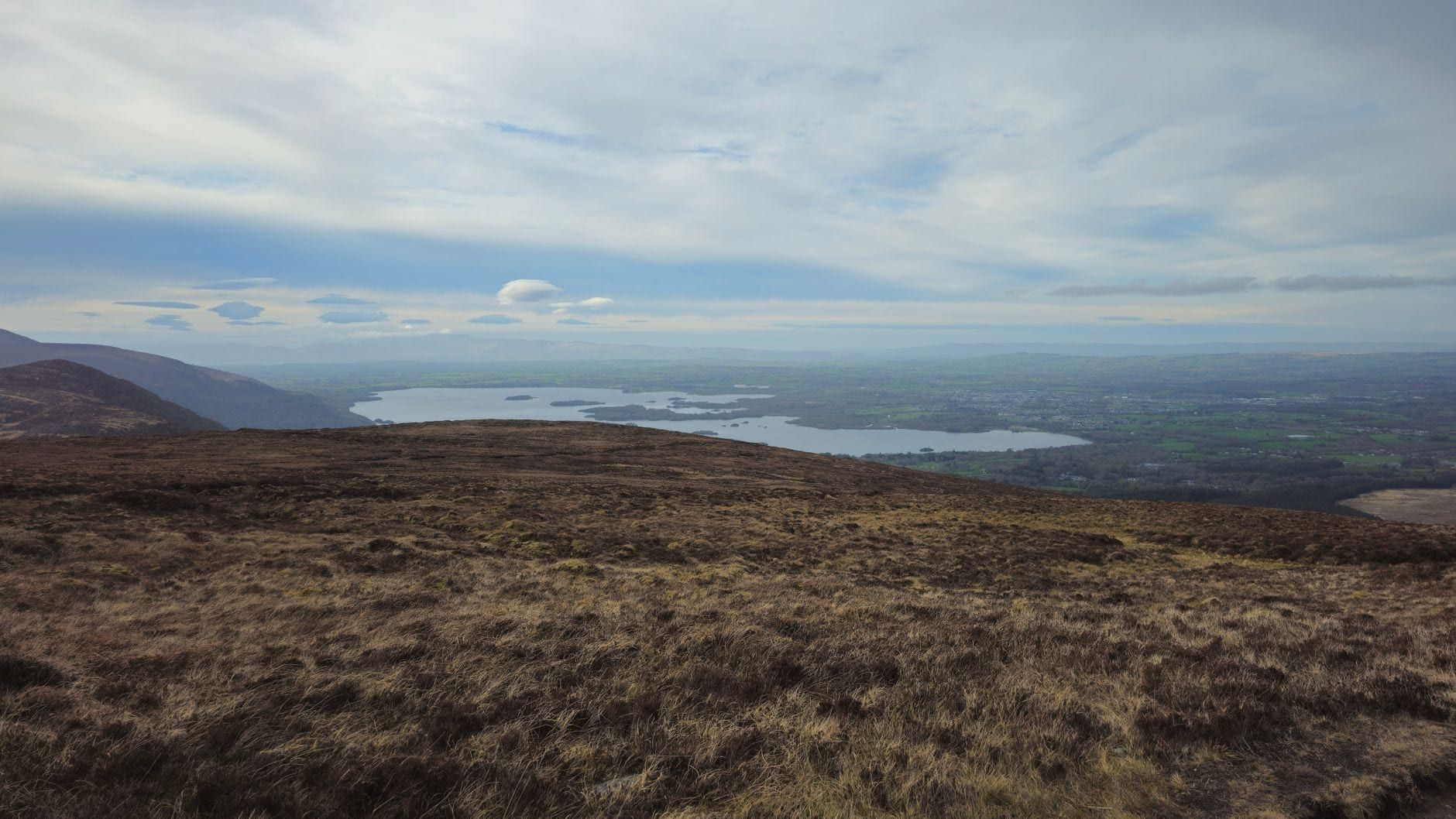 Panoramablick von einem Hang auf die Seen von Killarney entlang des Ring of Kerry unter einem bewölkten Himmel.