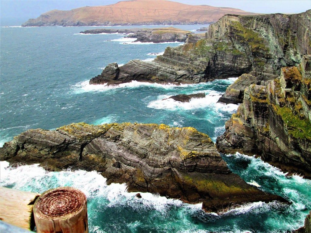 Dramatic sea cliffs and crashing turquoise waves along the Skellig Ring near Portmagee on the Ring of Kerry.