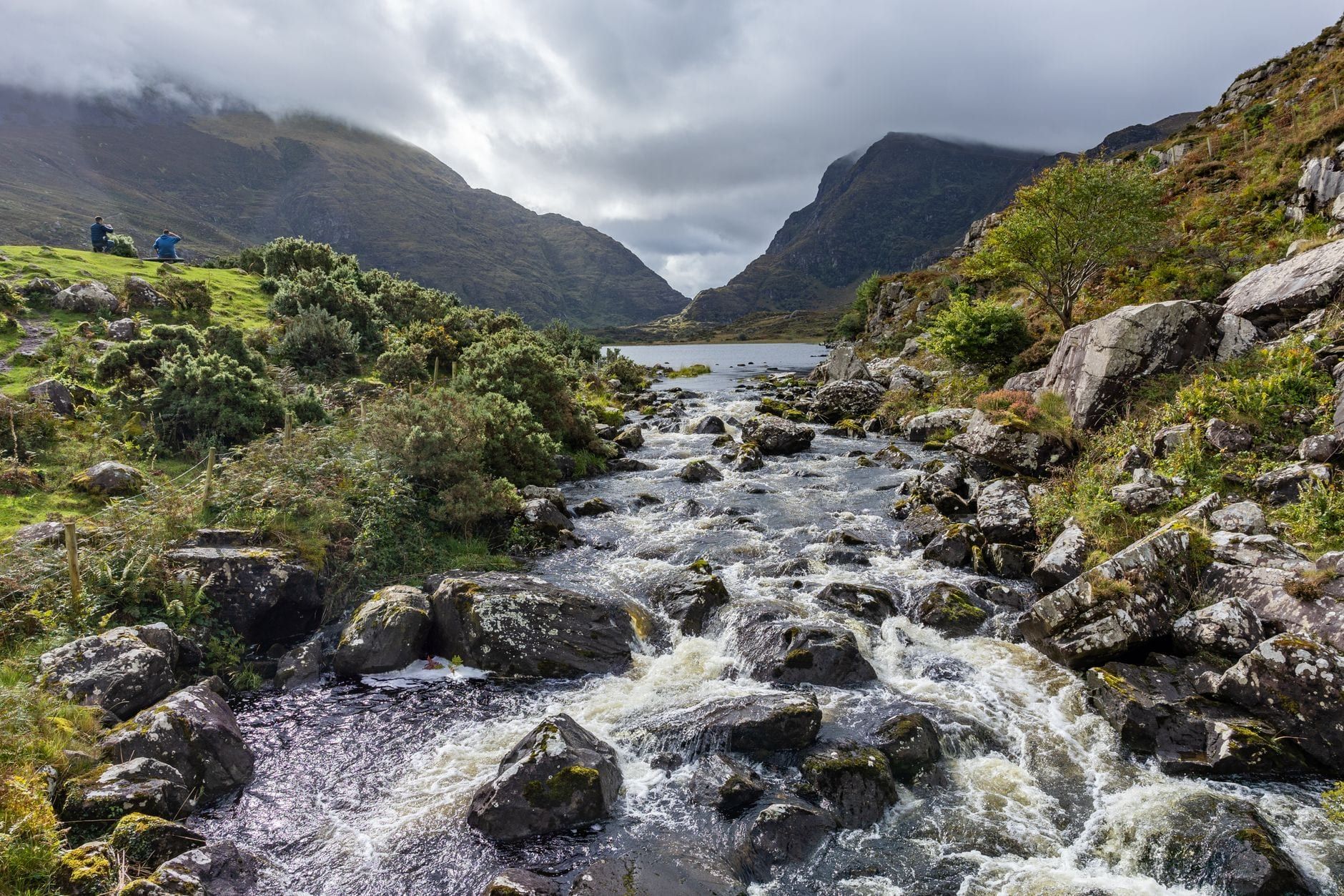 Ein felsiger Fluss stürzt durch den rauen Bergsattel des Gap of Dunloe entlang des Ring of Kerry in Irland herab.