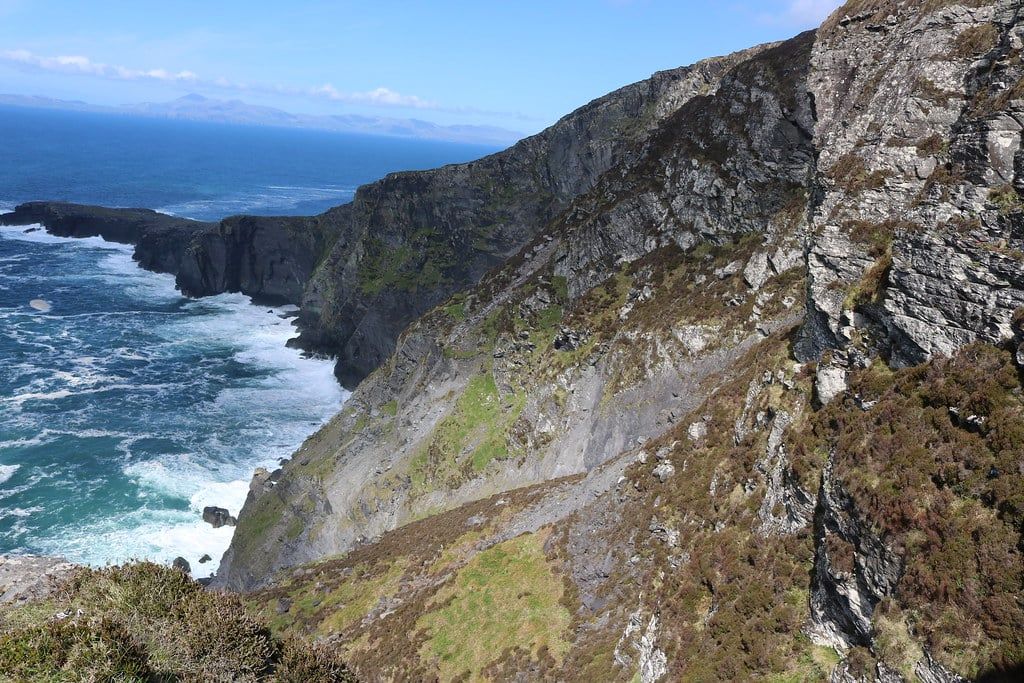 Steep rocky bluffs of the Fogher Cliffs drop down into the crashing ocean on Valentia Island along the Ring of Kerry.