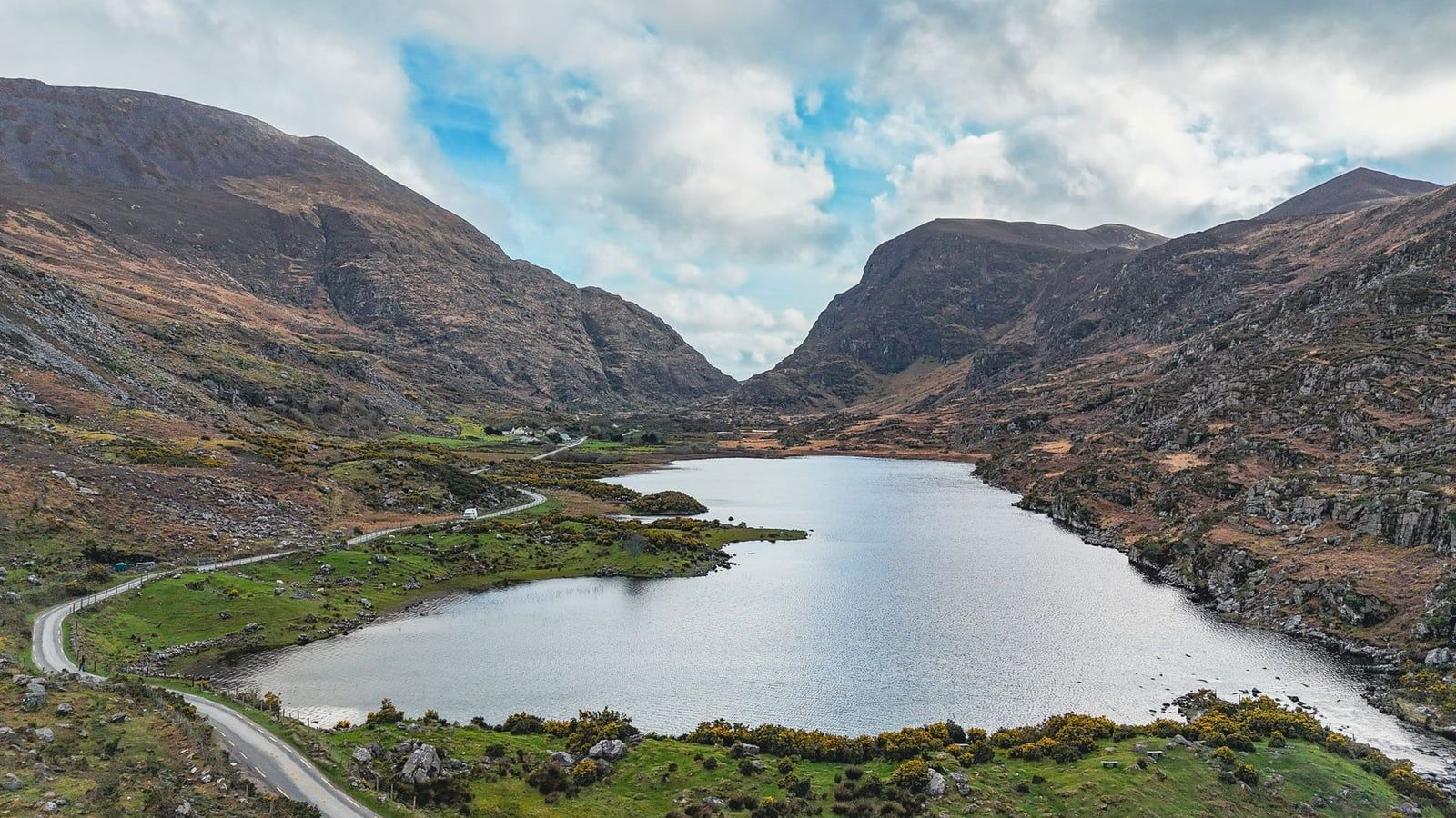 A winding road and lake framed by rugged mountain slopes in the Gap of Dunloe near the Ring of Kerry.