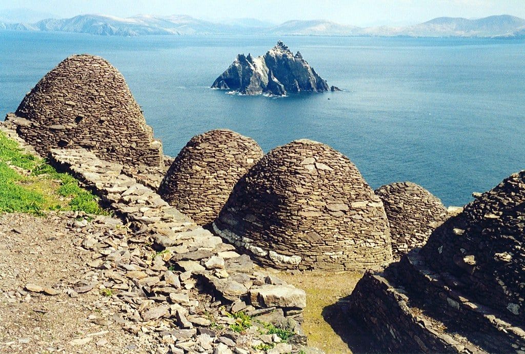 Antiche capanne in pietra a forma di alveare dell'insediamento monastico su Skellig Michael si affacciano sull'oceano verso Little Skellig lungo il Ring of Kerry.