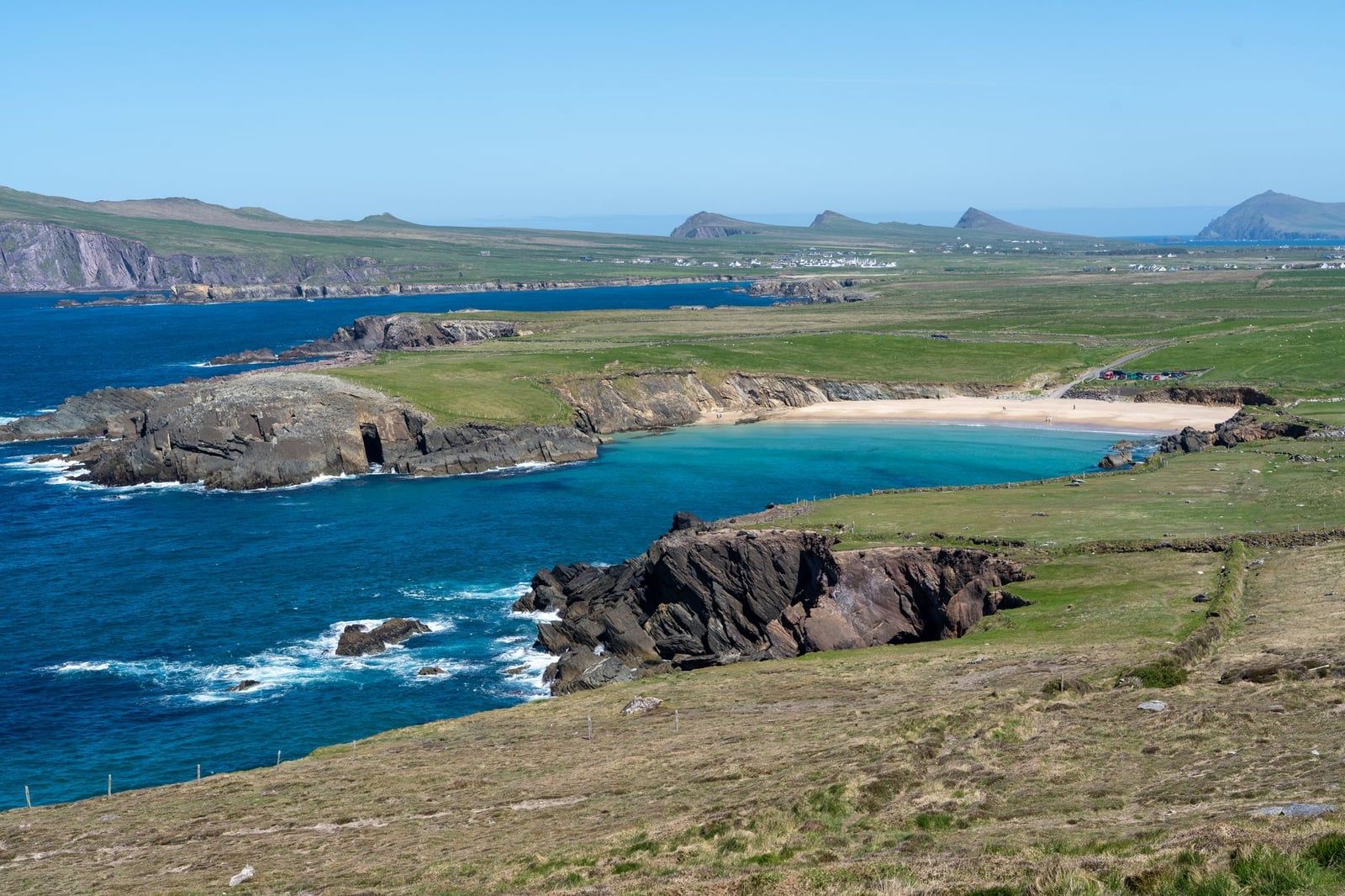 Ruvide scogliere costiere e una caletta sabbiosa si affacciano su acque turchesi lungo la Slea Head Drive sulla Penisola di Dingle, in Irlanda.