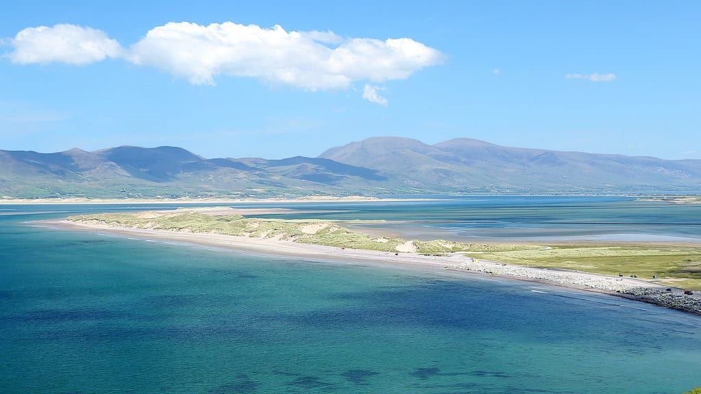 Wide panoramic view of Rossbeigh Beach and Dingle Bay backed by distant mountains along the Ring of Kerry.