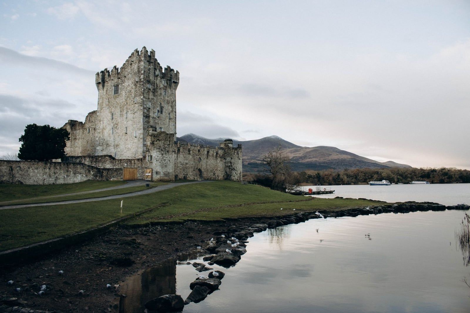 Stone walls and tower of Ross Castle stand along the shoreline of Lough Leane in Killarney on the Ring of Kerry.